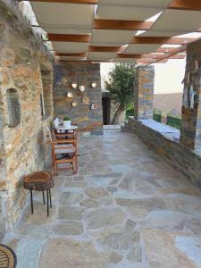 eine Terrasse mit einem Tisch, Stühlen und einer Steinmauer in der Unterkunft Gaia Vacation Home in Agia Mavra