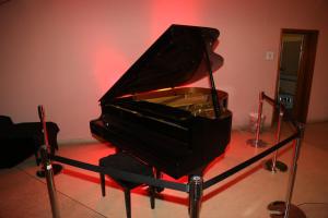 a black piano in a room with a red light at Schlosshotel Domäne Walberberg in Bornheim