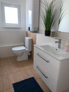 a white bathroom with a toilet and a sink at Amira Apartman in Komárno +15 photos