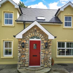 una casa amarilla con puerta roja en Holiday Cottages Portsalon en Portsalon