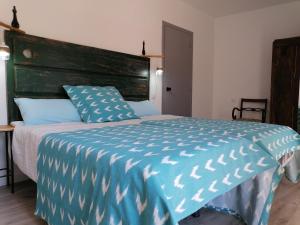 a bedroom with a large bed with a blue comforter at Ambroz y Plata in Aldeanueva del Camino