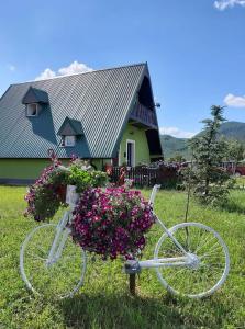 a white bicycle with flowers in front of a house at Villa Jasikovac in Berane