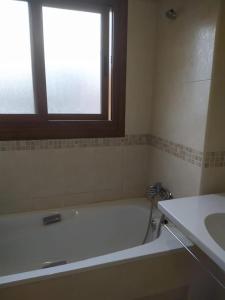 a bathroom with a tub and a sink and a window at Precioso adosado a 5 minutos de la playa de Miño in Miño