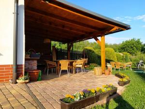 a patio with a wooden pavilion with chairs and flowers at Penzion Oliver in Žacléř