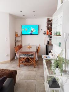 een woonkamer met een tafel en een tv aan de muur bij LES VAGUES, emplacement idéal, terrasse, rez-de-chaussée in Berck-sur-Mer