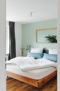 um quarto com uma grande cama branca com almofadas azuis em Rotes Haus Bregenz Wald Wohnung em Bregenz