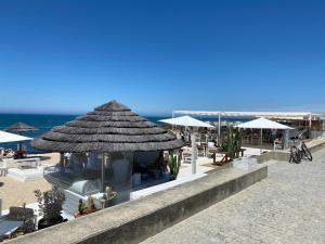 un bar sulla spiaggia con un ombrellone di paglia e l'oceano di Cozy Beach Front with Rooftop a Vila do Conde