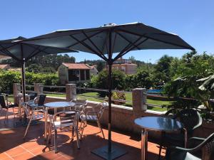 patio ze stołami i krzesłami pod parasolem w obiekcie Casa Fuentes w mieście Poio
