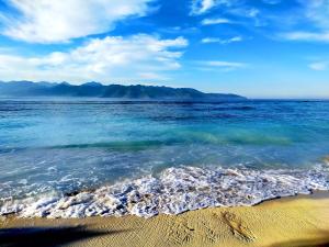 a beach with the ocean and mountains in the background at The Trawangan Resort in Gili Trawangan