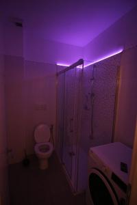 uma casa de banho com um WC e um chuveiro com luz roxa em casa David em Siena