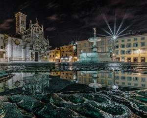 una piazza cittadina di notte con un riflesso nell'acqua di Hotel Giardino a Prato
