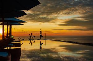 a pool with a person in the water at sunset at HAIAN Beach Hotel & Spa in Da Nang