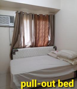 un letto in una stanza con tenda e finestra di Green Residence 23rd Floor a Manila