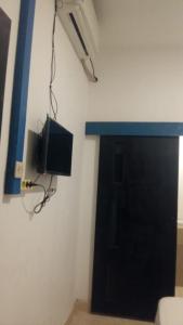 um quarto com uma porta preta e uma televisão na parede em Anyar rooms em Mataram