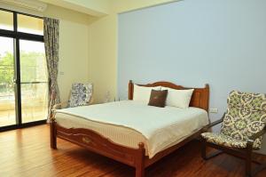 a bedroom with a bed and a chair and a window at Warm Home in Taitung City