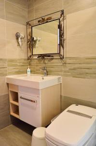 a bathroom with a sink and a toilet and a mirror at Warm Home in Taitung City