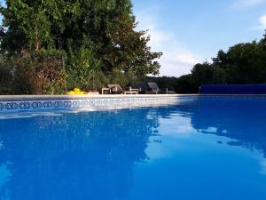 a blue swimming pool with two chairs and a table at Chez Savary in Varzay