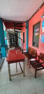 eine Terrasse mit 2 Bänken, einem roten Tisch und Stühlen in der Unterkunft Rumah Dempo Syariah in Sungaidurian