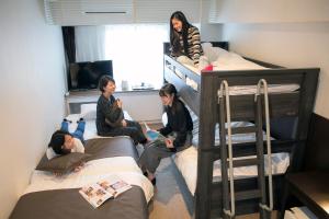 a group of people sitting on bunk beds in a room at Hotel Plaza Osaka in Osaka