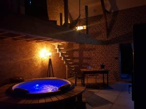 a hot tub in a dark room with a table at Odyssée - Chambre d'hôtes avec spa et sauna privés in Zeggers-Cappel