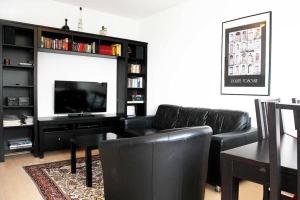 ein Wohnzimmer mit schwarzen Ledermöbeln und einem Flachbild-TV in der Unterkunft City Apartments Cologne - Apartment 2 in Köln