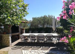 a table and chairs with an umbrella and some flowers at Rab Pandelo Apartmani in Rab