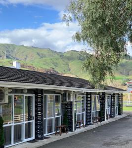 un edificio con ventanas blancas y negras y montañas en Racecourse Motel, en Paeroa