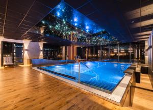 a large swimming pool in a building with lights at Caryńska Resort & SPA in Lutowiska