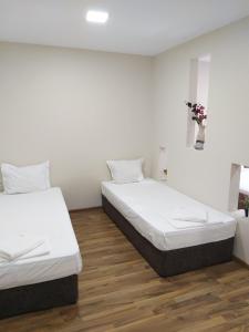 twee bedden in een kamer met witte muren en houten vloeren bij Radi Inn in Svilengrad