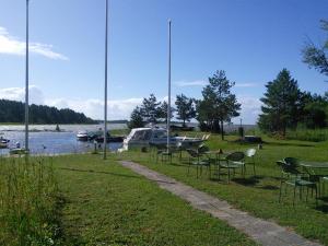 een groep stoelen en tafels en een boot op het water bij Paatsalu Camping in Paatsalu