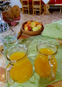two glasses of orange juice on a table with a bowl of apples at Rooms & Apartments Pr Matjon in Bled