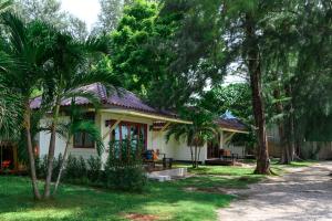 a small white house with palm trees in the yard at Wapi Resort in Ko Lipe