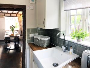 a kitchen with a white sink and a table at Millie's Cottage in Finchingfield