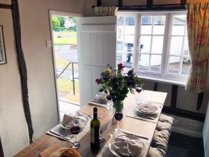 a table with glasses of wine and a vase of flowers at Millie's Cottage in Finchingfield