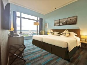 um quarto de hotel com uma cama grande e uma janela grande em Thistle Johor Bahru em Johor Bahru