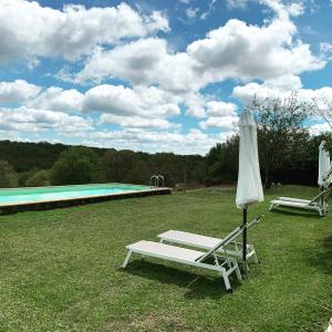 einen weißen Sessel und einen Sonnenschirm neben einem Pool in der Unterkunft Chambres d'hôtes Pech Blanc in Calvignac