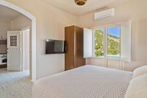 a white bedroom with a bed and a window at Lux View Suites in Kyra Panagia