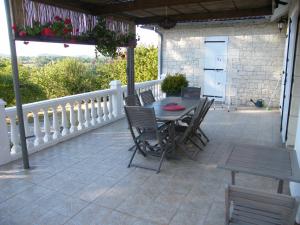 a patio with a table and chairs on a porch at Lou Malinbouzat in Brignac-la-Plaine