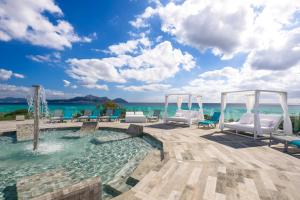 a pool with chairs and the ocean in the background at Playa Garden Selection Hotel & Spa in Playa de Muro