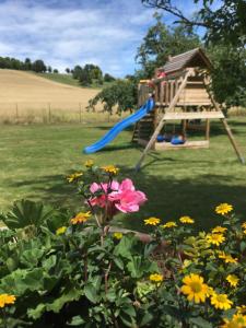 a playground with a blue slide and flowers at La Maisonnette Dintevilloise in Dinteville