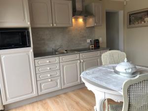 uma cozinha com armários brancos e uma mesa com cadeiras em Au refuge du spéléo em Hotton