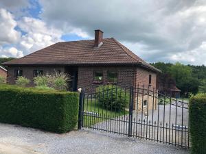 a brick house with a gate in front of it at Au refuge du spéléo in Hotton