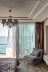 1 dormitorio con cama, silla y ventana grande en Maristella Marine Residense Hotel Apartment en Odesa
