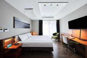 a hotel room with a bed and a desk and a television at Felix by STX Hotel & Suite in Busan