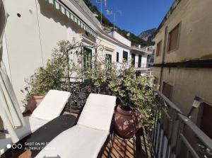 a balcony with white chairs and plants on a building at Residenza Del Duca Rooms & Apartments in Amalfi