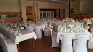 a room filled with white tables and white chairs at Hotel & Gasthaus Zum Eichenkranz in Luckenwalde