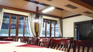un comedor con mesas, sillas y ventanas en Borika Hotel, en Chepelare