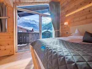 a bedroom with a bed and a large window at Chalet Elisabeth dolomites alpin & charme in Selva di Val Gardena