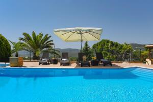 uma piscina com espreguiçadeiras e um guarda-sol em Hotel Rural Rocha da Gralheira em São Brás de Alportel