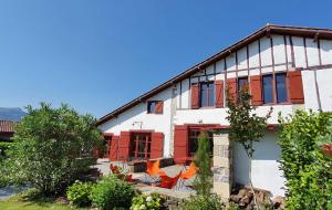 a house with red shutters and chairs in front of it at La ferme d'Ika in Saint-Jean-de-Luz
